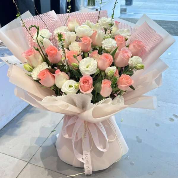 Bouquet of pink and white roses with ribbon in a wrapped presentation