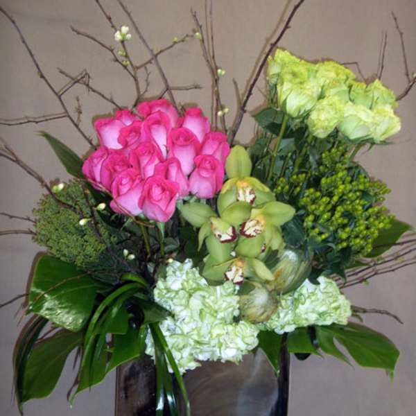 Pink roses and green orchids in a square vase with branches