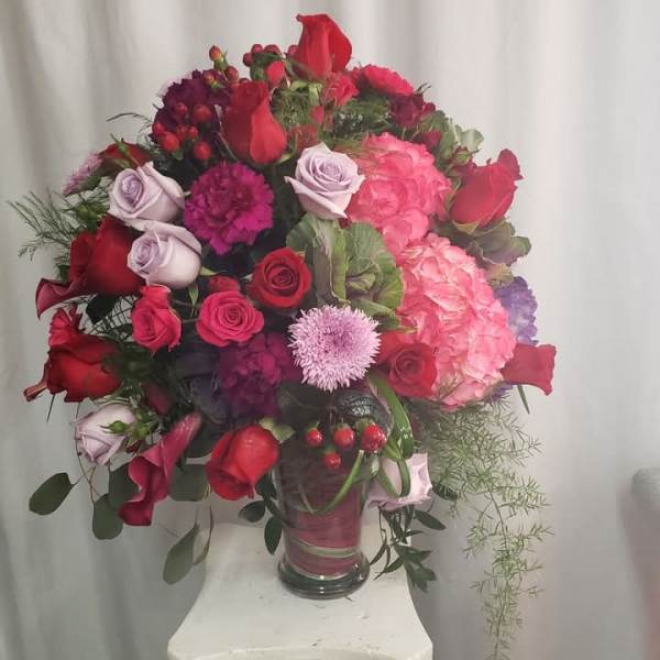 Large bouquet of red, pink, and lavender flowers in a glass vase