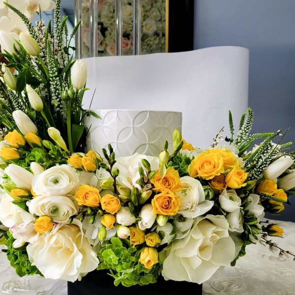 White and yellow floral arrangement with roses and tulips in a white vase
