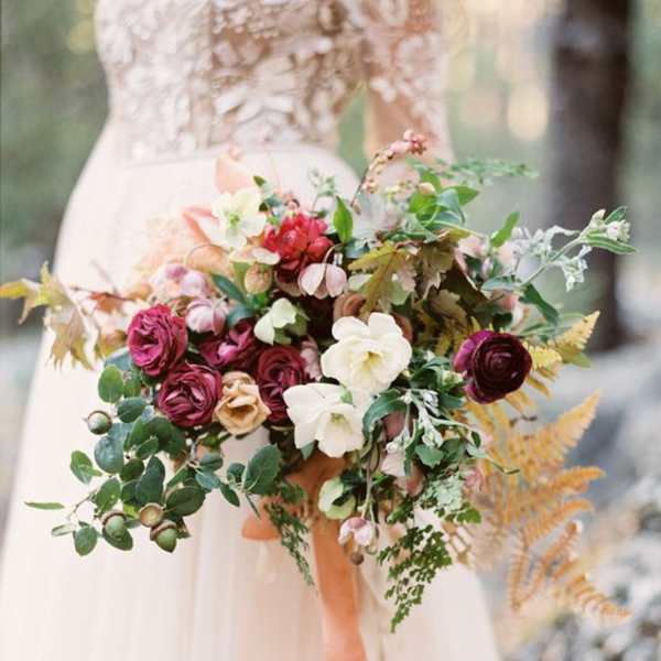 Bride holding a cascading bouquet of burgundy, white, and blush flowers