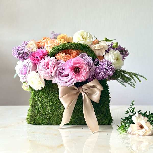 Colorful bouquet in a moss-covered box with a satin bow