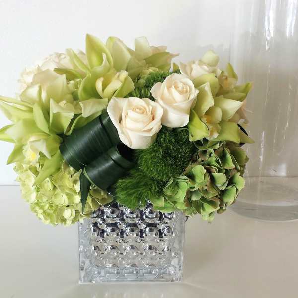 Green and cream floral arrangement in a clear textured vase