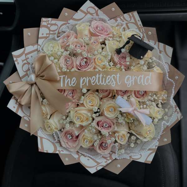 Bouquet of pink and cream roses with a graduation ribbon and cap decoration