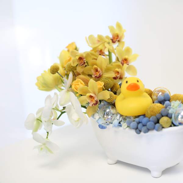 Yellow and white orchids in a white bowl with a small rubber duck