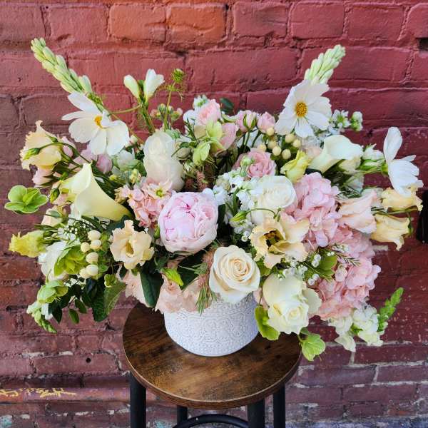 Large pastel floral arrangement in a white vase
