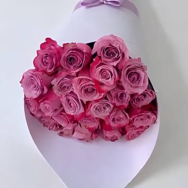 Bouquet of pink roses wrapped in white paper with a lavender ribbon