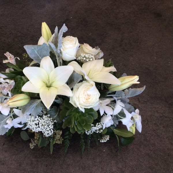 White lilies and roses arranged with pale blue foliage