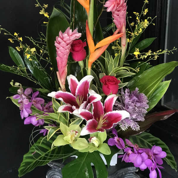 Tropical floral arrangement with pink lilies, roses, and orchids