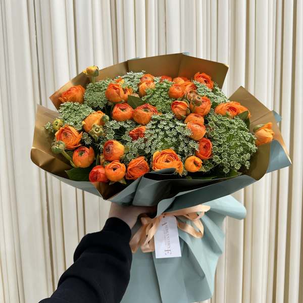Bouquet of orange ranunculus wrapped in blue paper