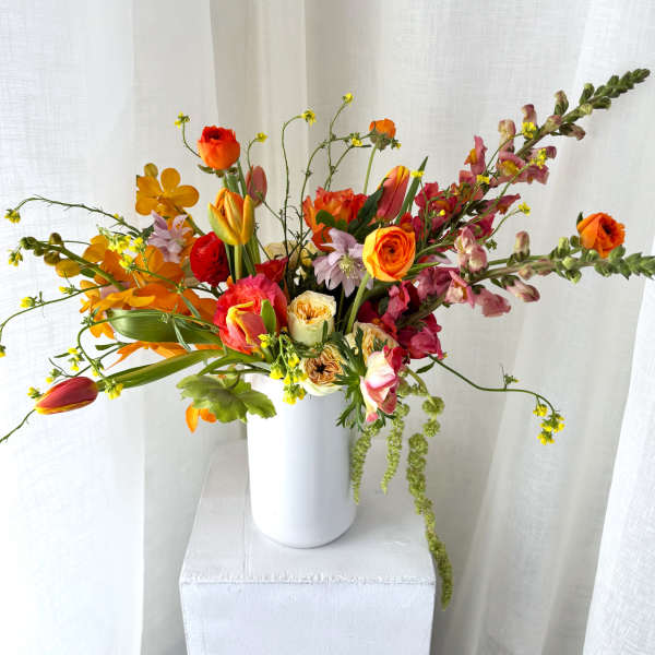 Mixed bouquet in a white vase with orange, pink, and yellow flowers