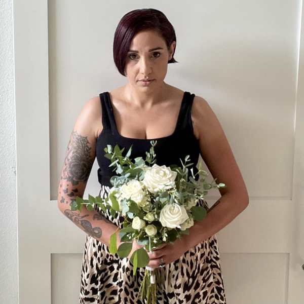 Woman holding a bouquet of white roses and greenery