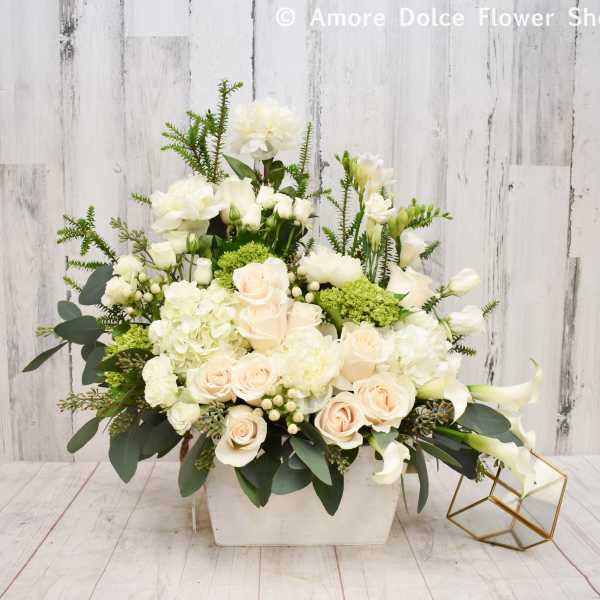 White and blush floral arrangement in a rectangular vase with calla lilies and roses