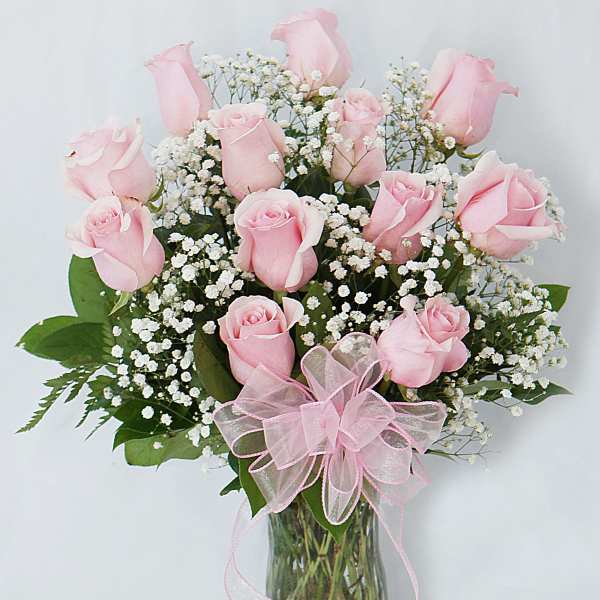 Pink roses in a glass vase with baby's breath and a pink ribbon