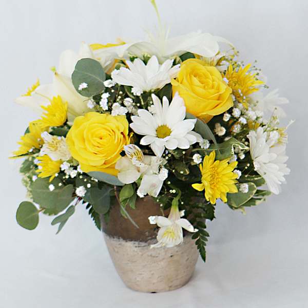 Yellow roses and white daisies in a rustic pot