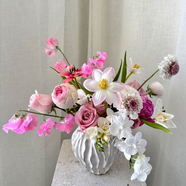 Pink and white floral arrangement in a white textured vase