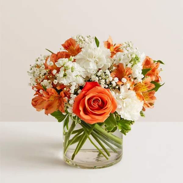 Orange and white flowers arranged in a clear glass vase
