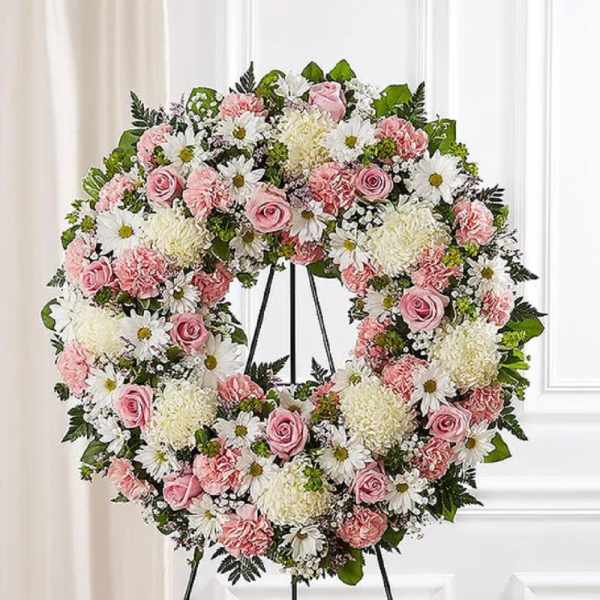 Pink and white floral wreath on a black stand
