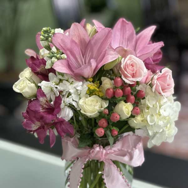 Pink and white mixed bouquet in a glass vase with a pink ribbon