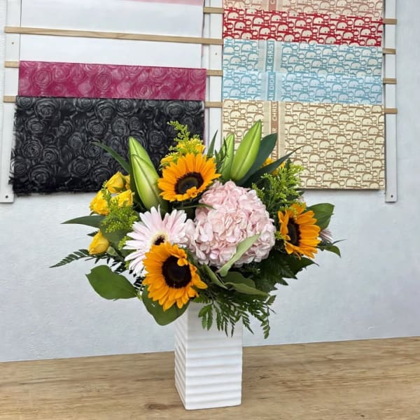 Sunflower and hydrangea arrangement in a white vase