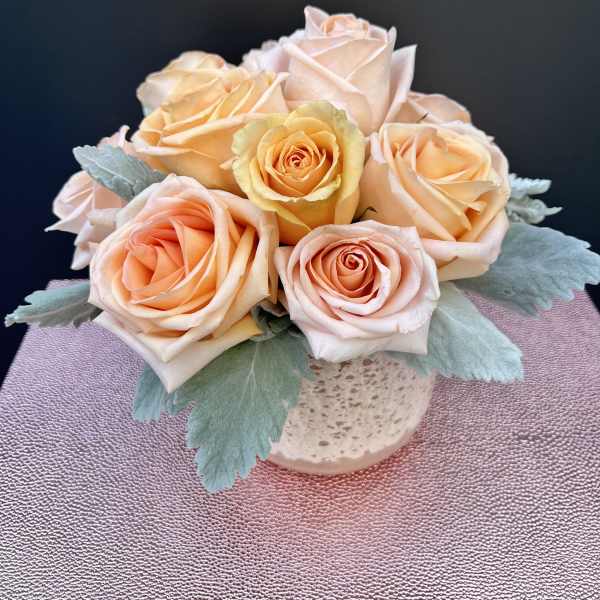 Peach and blush roses arranged in a small vase
