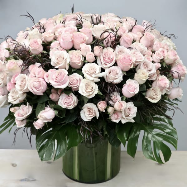 Large bouquet of pale pink and white roses in a green glass vase