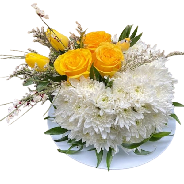 Low arrangement of yellow roses and tulips with white mums on a white plate