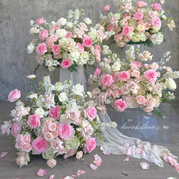 Pink and white rose arrangements with trailing fabric on clear stands