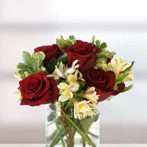 Red roses and pale lilies in a clear glass vase
