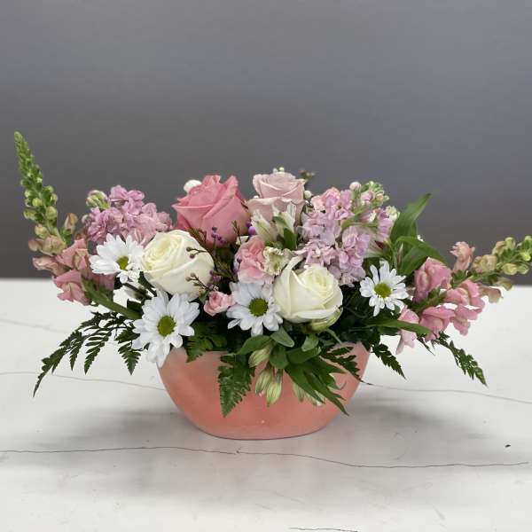 Pink and white flower arrangement in a peach bowl vase