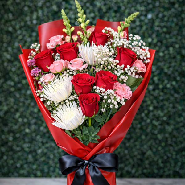 Bouquet of red and pink roses with white blooms wrapped in red paper