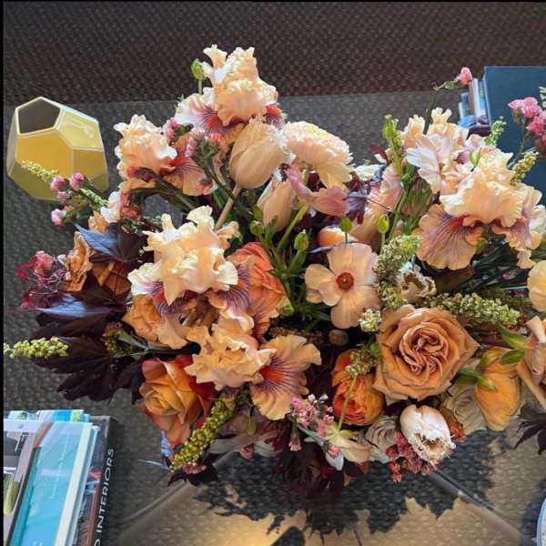 Peach and cream floral arrangement with roses and iris on a table