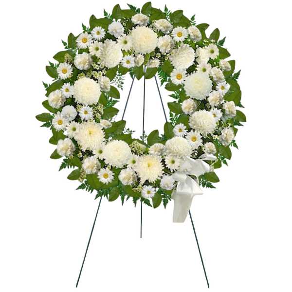 White floral funeral wreath on a stand with a ribbon bow
