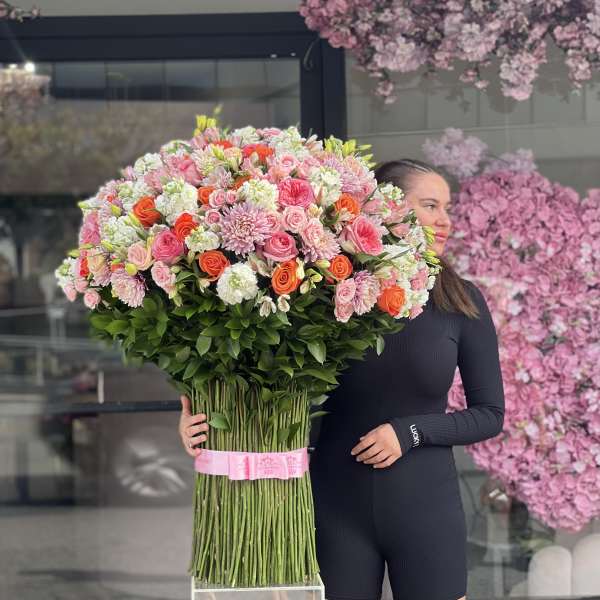 Large bouquet of pink and orange flowers held by a woman