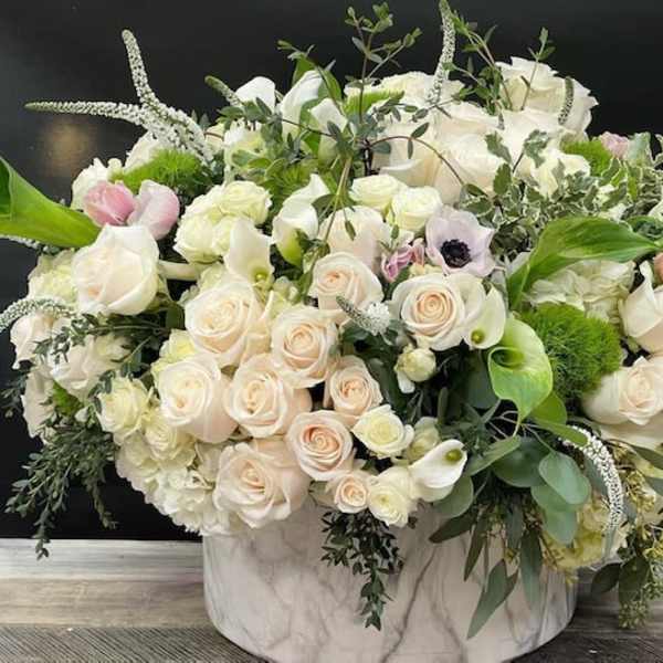 Large white and blush rose arrangement in a marble-patterned vase