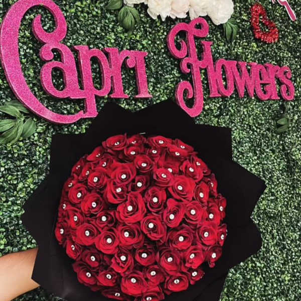 Bouquet of red roses wrapped in black paper against a green backdrop