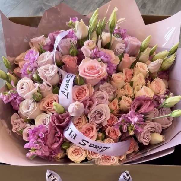 Large pink bouquet of roses and lisianthus in pastel wrapping