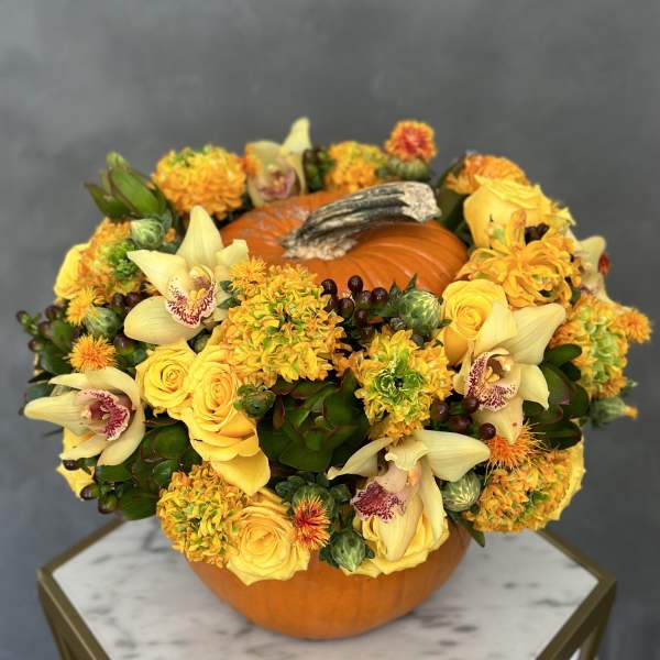 Pumpkin centerpiece with yellow flowers and orchids