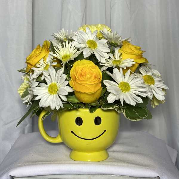 Yellow smiley-face mug filled with yellow roses and white daisies