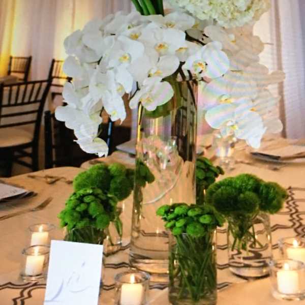 White orchid and hydrangea centerpiece in a tall glass vase