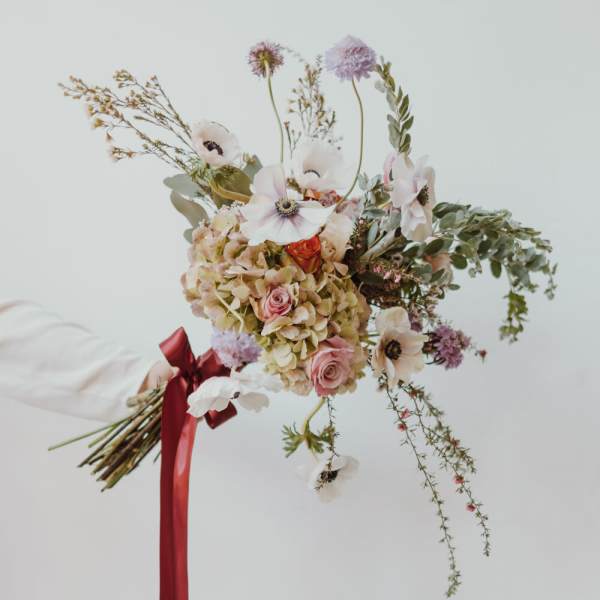 Loose bouquet of pale flowers with a red ribbon tie