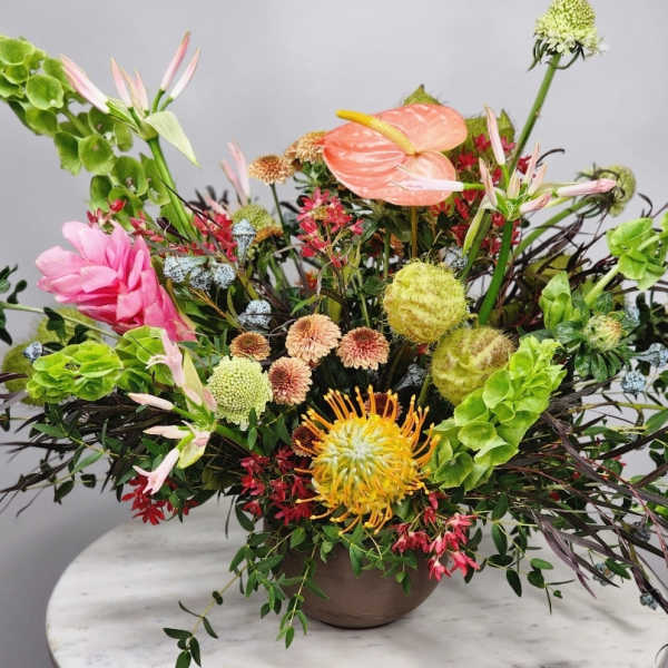 Mixed floral arrangement in a brown vase with pink, green, and yellow blooms