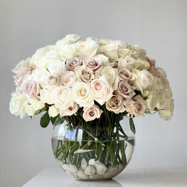 Round bouquet of pale roses in a clear glass bowl vase