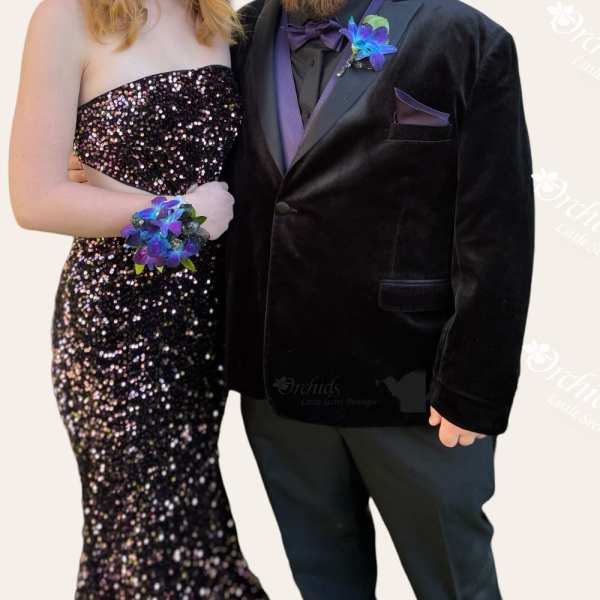 Formal couple wearing matching purple floral wrist corsages and boutonniere
