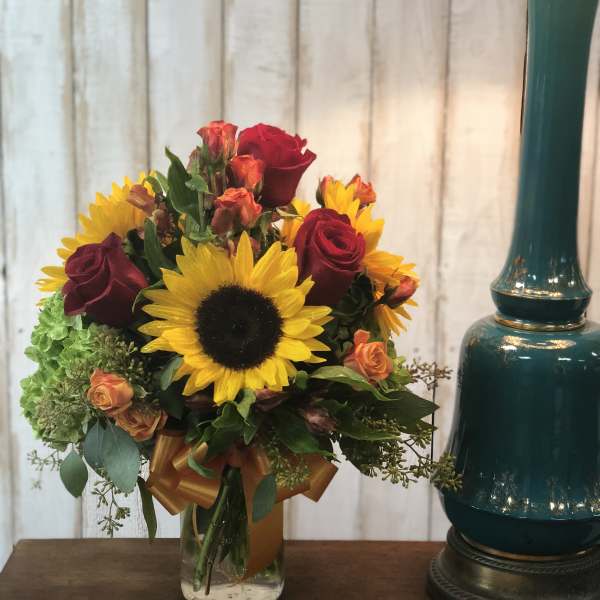 Bouquet of sunflowers and red roses in a glass vase