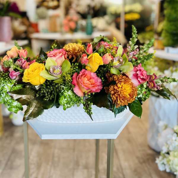 Colorful mixed flower arrangement in a white pedestal vase