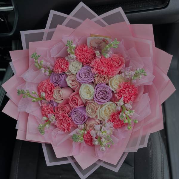 Pink bouquet of roses and carnations wrapped in layered pink paper