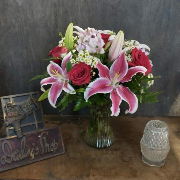 Bouquet of pink lilies and red roses in a glass vase
