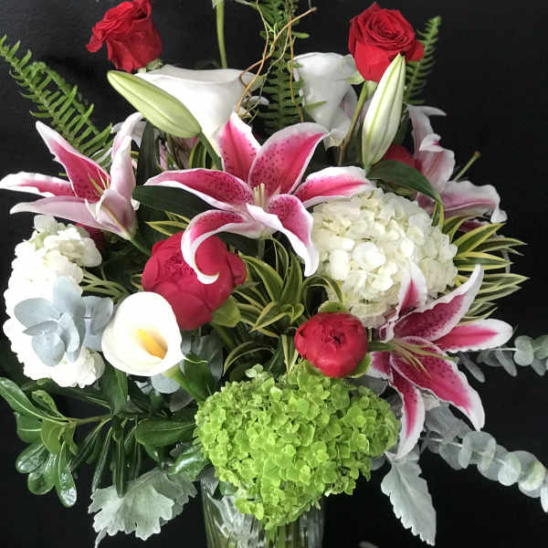 Bouquet of red roses, pink lilies, and white hydrangea in a glass vase