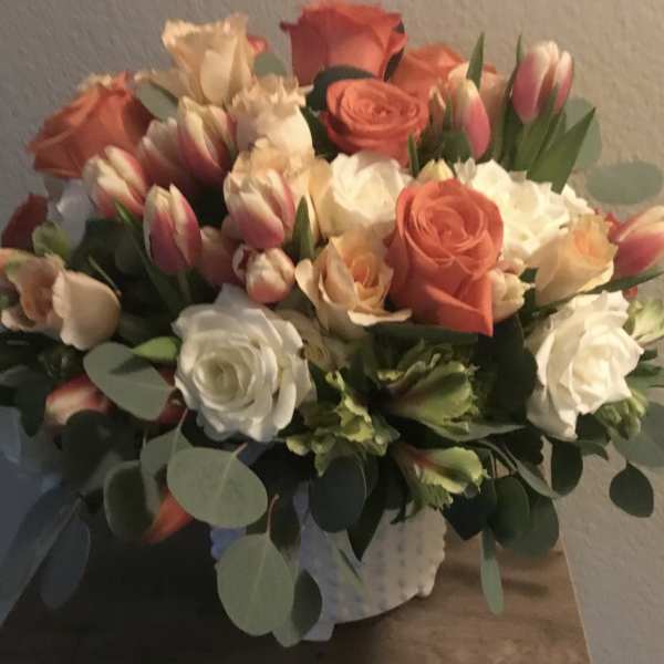 Bouquet of coral and white roses with pink tulips in a wrapped container